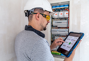 Commercial electrical, refrigeration & HVAC Electrical technician looking focused while working in a switchboard with fuses.